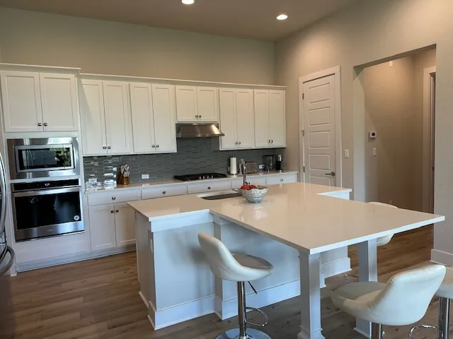 a kitchen with kitchen island a stove a table and chairs