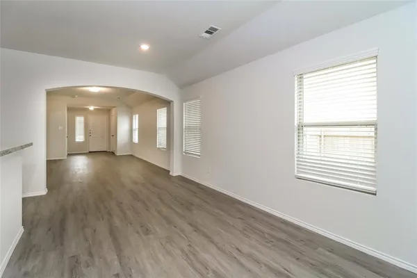 a view of an empty room with wooden floor and a window