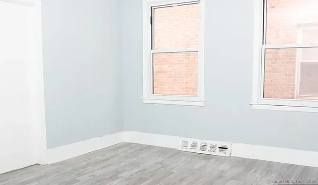 an empty room with wooden floor and windows
