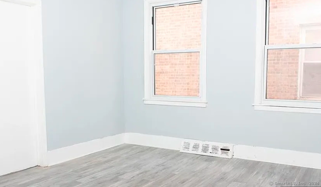 301 Dover Street, Unit 2 Bridgeport, CT 06610 - Photo 2 of 2 an empty room with wooden floor and windows