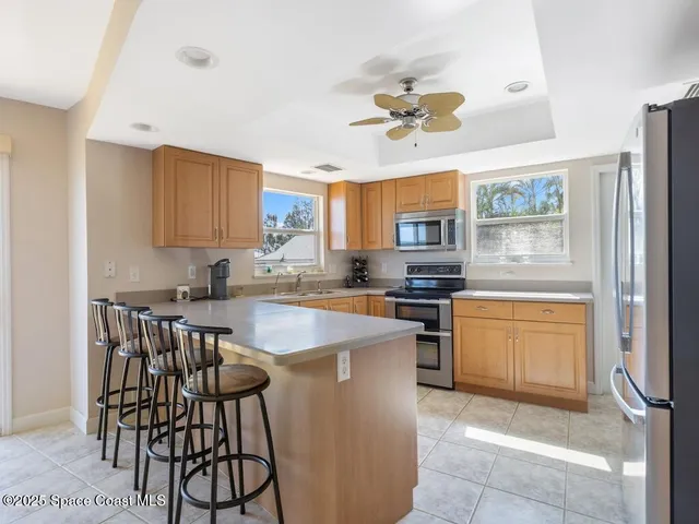 a kitchen with stainless steel appliances granite countertop a stove top oven a sink a dining table and chairs with wooden floor