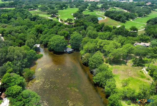 an aerial view of residential house with outdoor space and trees all around