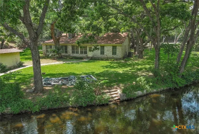 a view of a house with a yard and a large tree