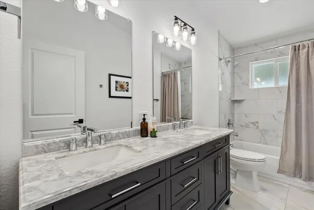 a bathroom with a granite countertop sink a toilet and shower