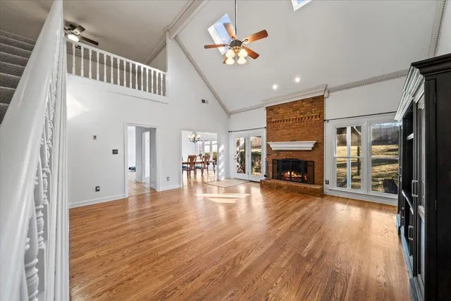 an empty room with wooden floor fireplace and windows