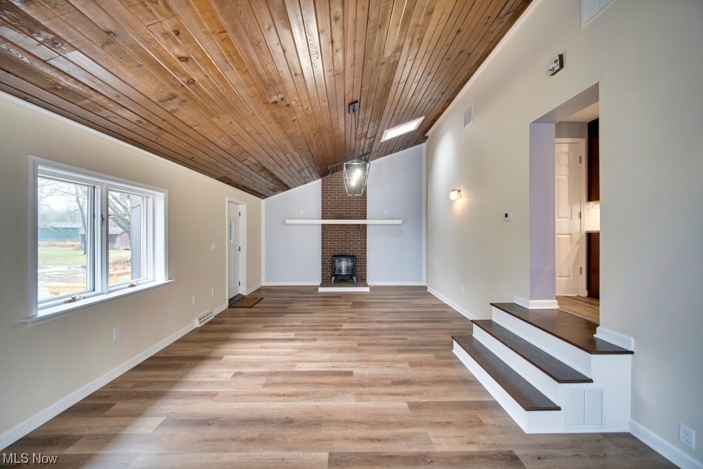 7060 Lear Nagle Road North Ridgeville, OH 44039 - Photo 14 of 29 Unfurnished living room with wooden ceiling, brick wall, vaulted ceiling, light hardwood / wood-style flooring, and a fireplace