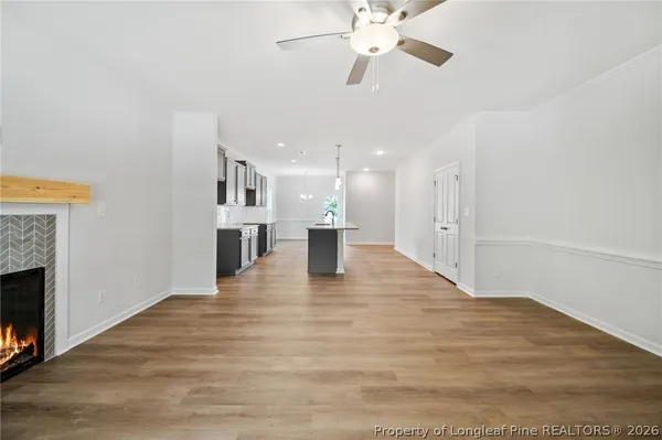 a view of an empty room and kitchen view with wooden floor