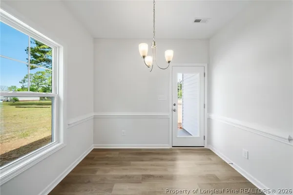 an empty room with wooden floor mirror and windows
