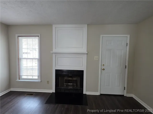 an empty room with wooden floor a fireplace and windows