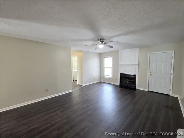 an empty room with wooden floor fireplace and windows