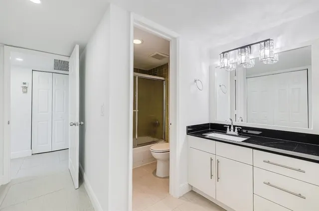 a bathroom with a granite countertop sink a toilet a mirror and shower