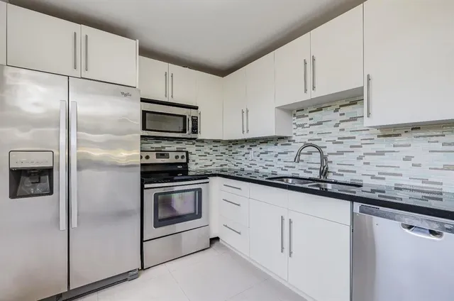 a kitchen with granite countertop white cabinets white stainless steel appliances and sink
