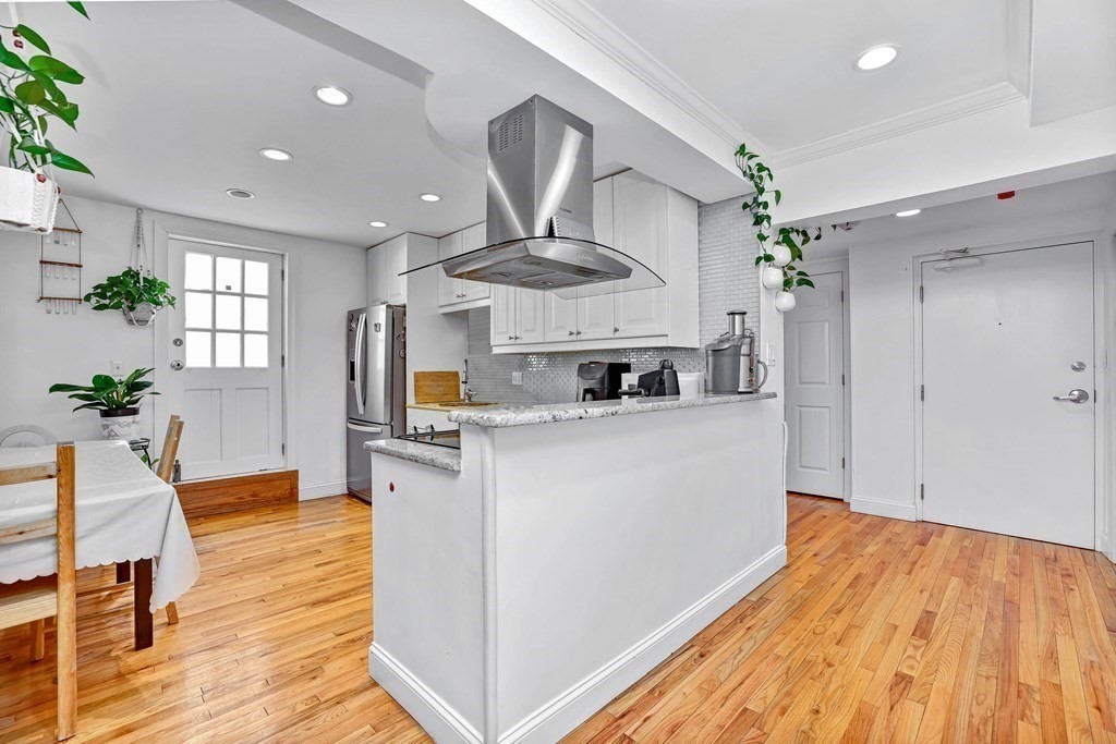 16 Addington Road, Unit 23 Brookline, MA 02445 - Photo 3 of 21 a kitchen with stainless steel appliances granite countertop a refrigerator a stove a sink dishwasher and a dining table with wooden floor