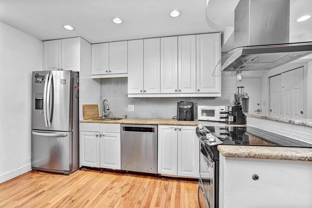 16 Addington Road, Unit 23 Brookline, MA 02445 - Photo 4 of 21 a kitchen with granite countertop wooden floors and stainless steel appliances