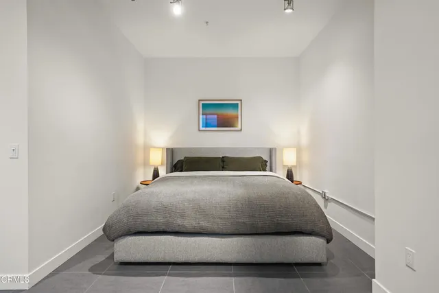 a spacious bedroom with a bed a chandelier and glass door