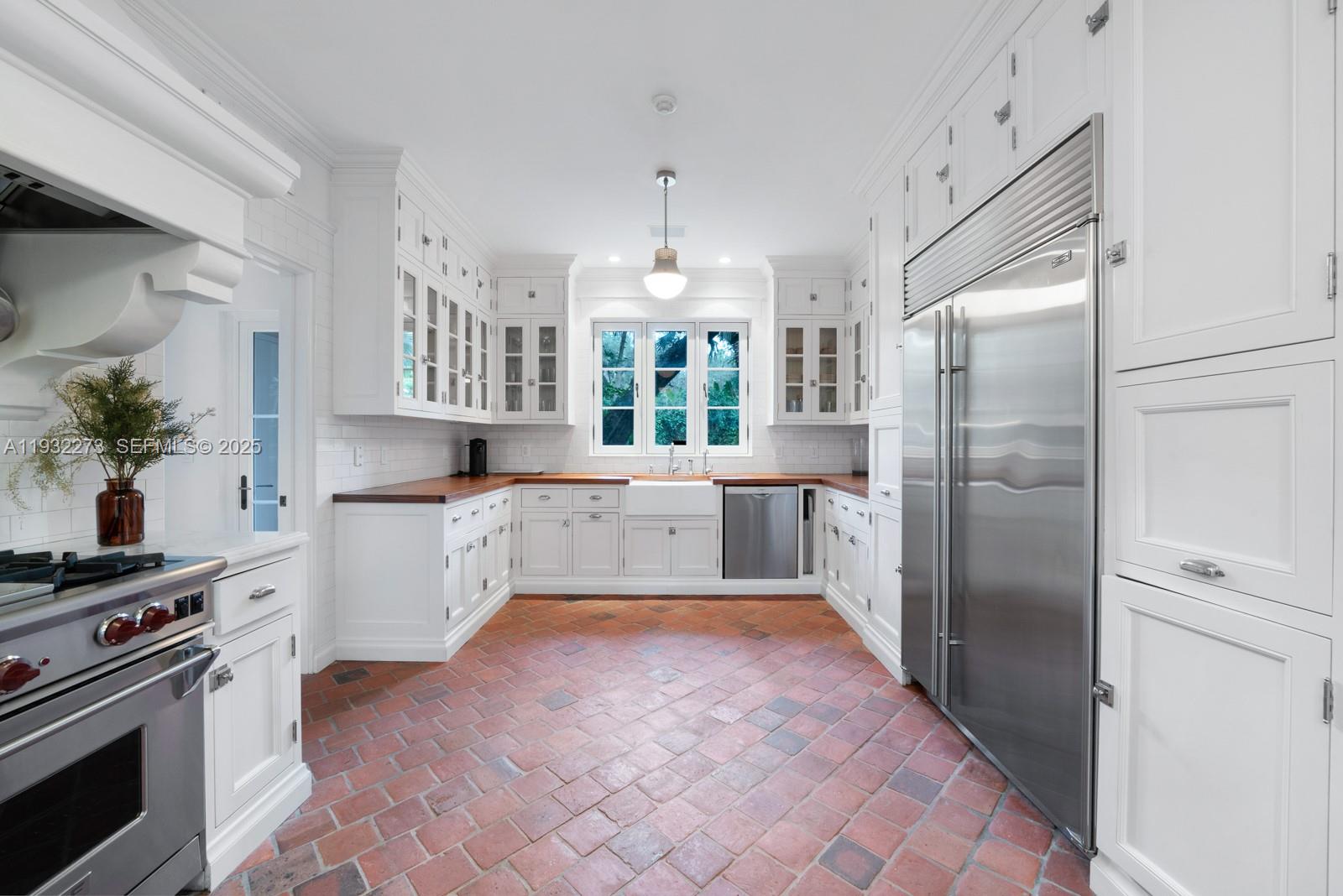 3467 North Moorings Way Miami, FL 33133 - Photo 10 of 25 a large white kitchen with a refrigerator a stove a sink and a window