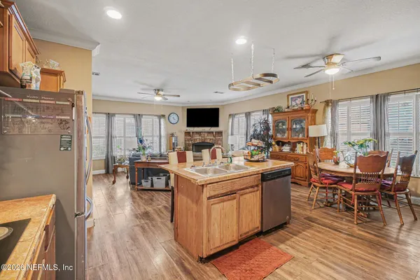 a open kitchen with stainless steel appliances granite countertop a stove top oven a sink dishwasher and white cabinets with wooden floor