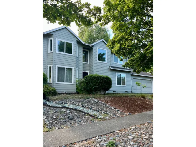 a view of a house with a yard and large tree