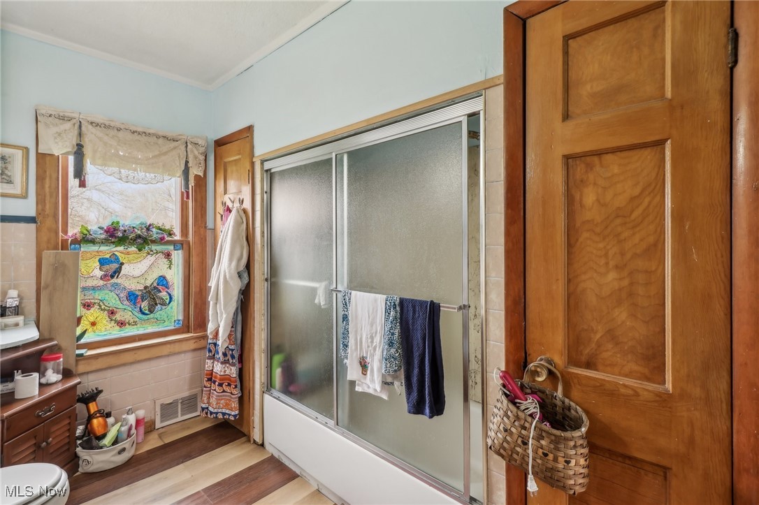 944 Bey Road Akron, OH 44312 - Photo 23 of 47 Full bathroom with shower / bath combination with glass door, toilet, visible vents, wood finished floors, and ornamental molding