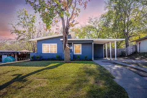 a view of a house with a yard and large tree
