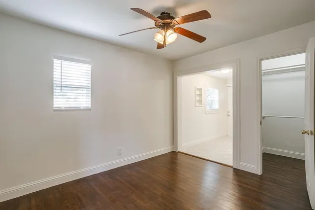 an empty room with wooden floor fan and windows