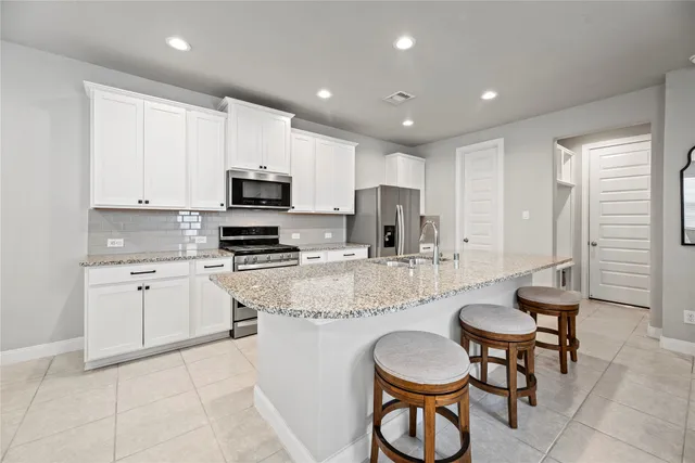 a kitchen with stainless steel appliances granite countertop a stove a sink a dining table and chairs