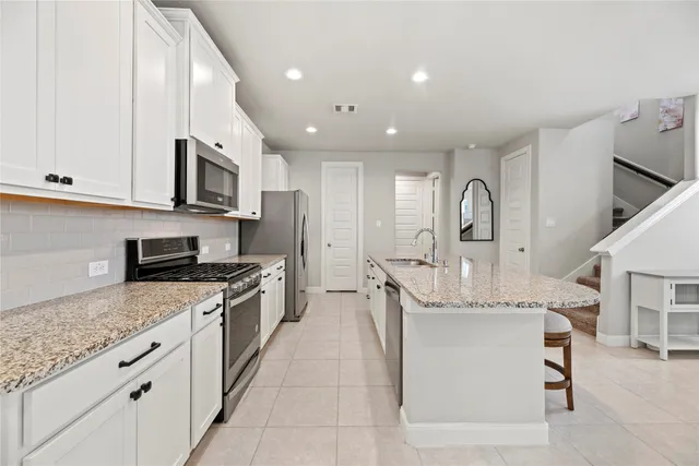 a large kitchen with stainless steel appliances granite countertop a sink a stove and cabinets