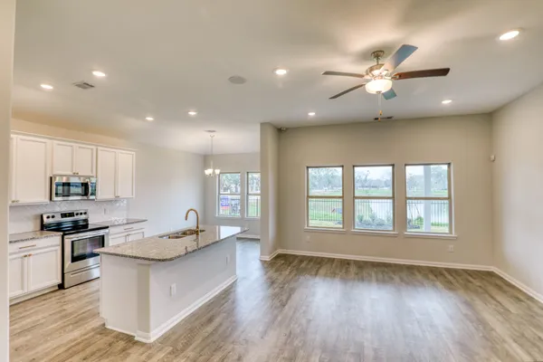 a large kitchen with stainless steel appliances a large counter top a stove a sink and a refrigerator