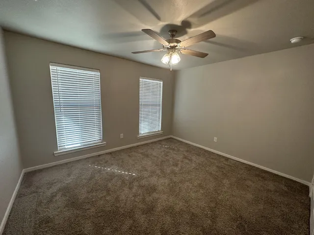 an empty room with windows and fan