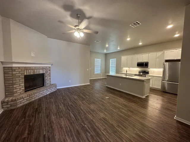 a open kitchen with kitchen island a sink dishwasher a stove and a refrigerator with wooden floor