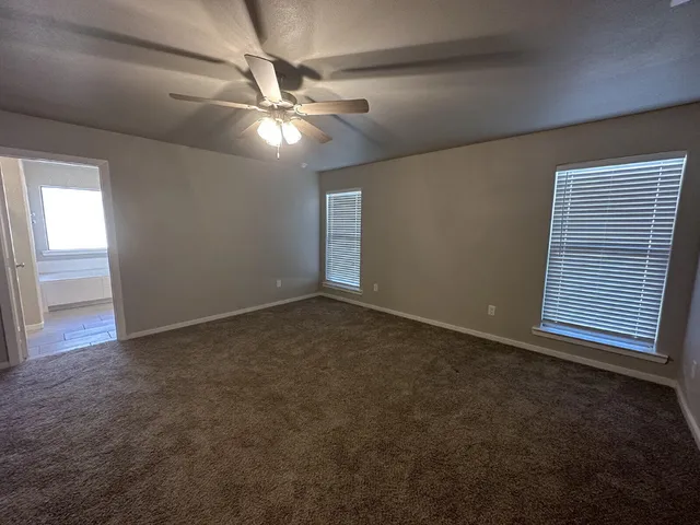 an empty room with windows and fan