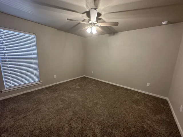 an empty room with a chandelier fan and windows