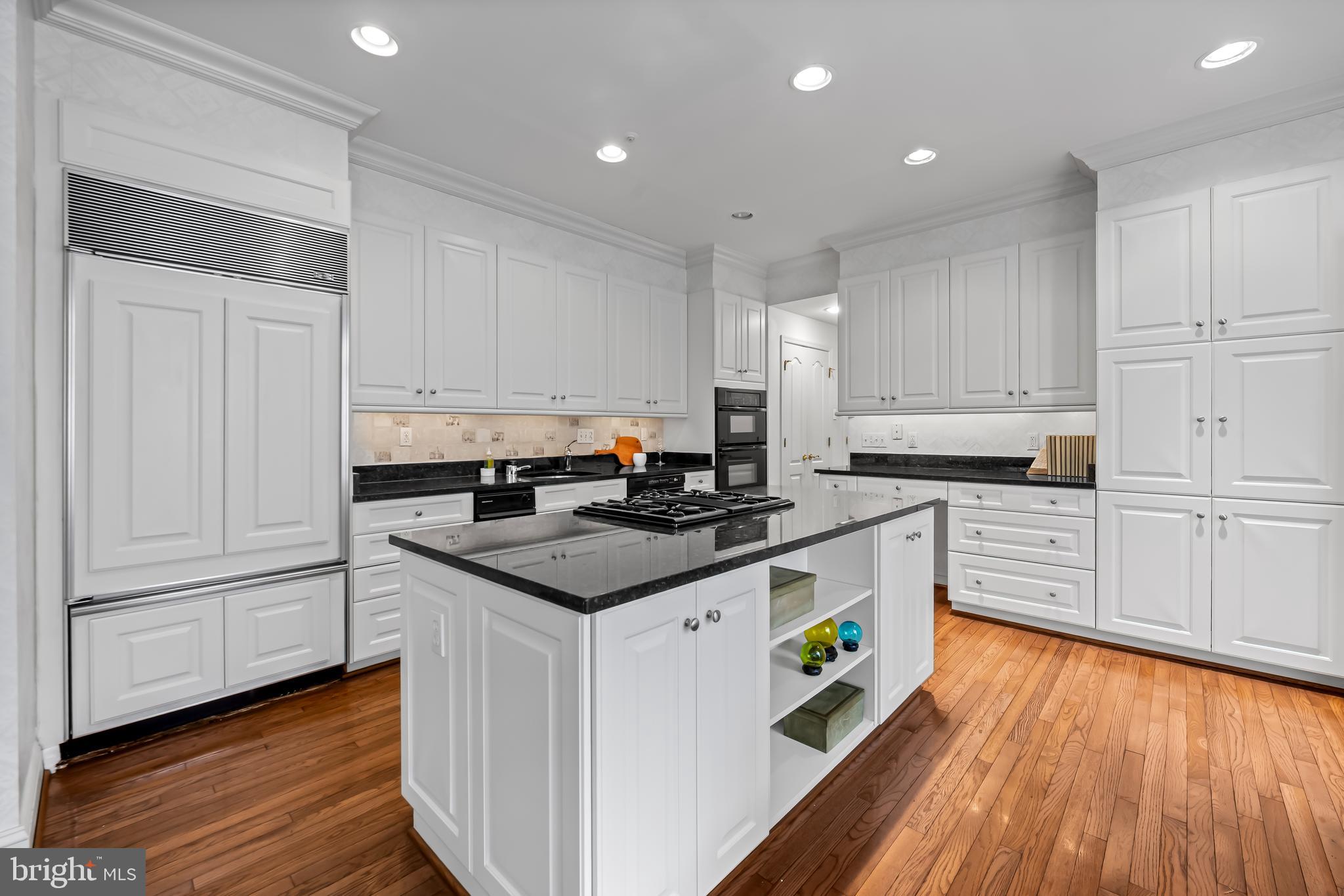 24 Roland Green, Unit 12 Baltimore, MD 21210 - Photo 13 of 53 a kitchen with granite countertop a white stove top oven and white cabinets with wooden floor