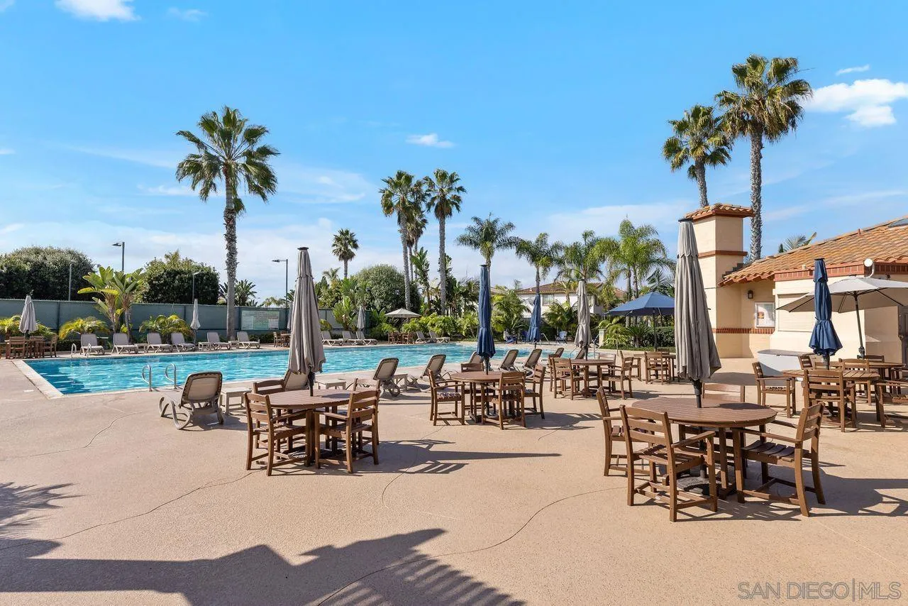 7390 Seafarer Place Carlsbad, CA 92011 - Photo 32 of 41 a view of a patio with dining table and chairs potted plants and palm tree