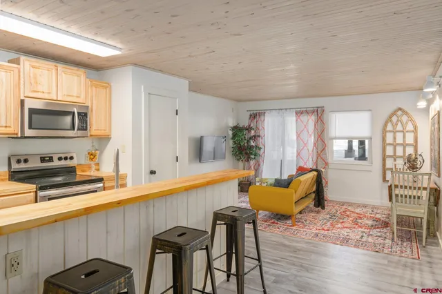 a kitchen with stainless steel appliances granite countertop a stove top oven a sink dishwasher a dining table and chairs with wooden floor