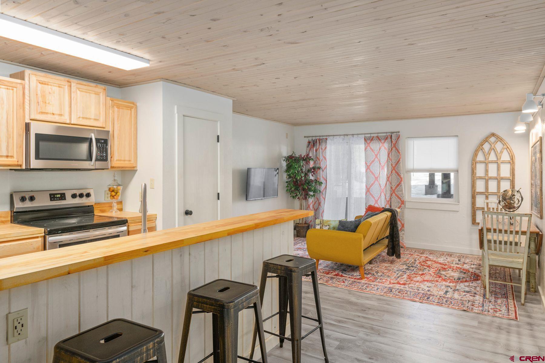 a kitchen with stainless steel appliances granite countertop a stove top oven a sink dishwasher a dining table and chairs with wooden floor