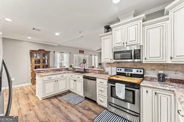 a kitchen with granite countertop a refrigerator stove top oven and cabinets