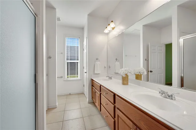 a spacious bathroom with a double vanity sink a mirror and a shower