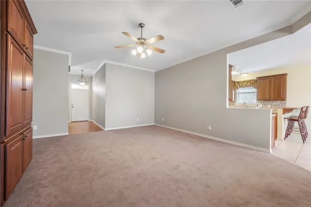 a view of an empty room with a chandelier fan