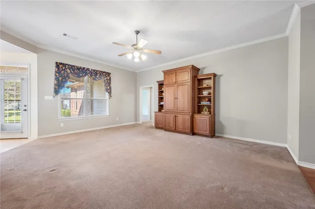 an empty room with windows and chandelier fan