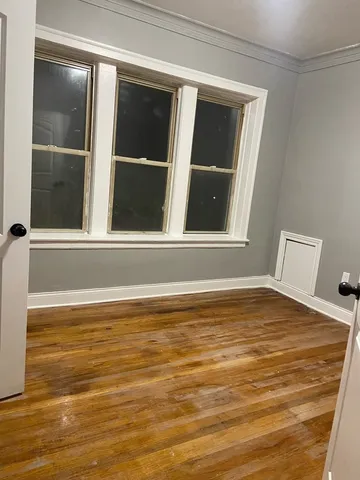a view of empty room with window and wooden floor