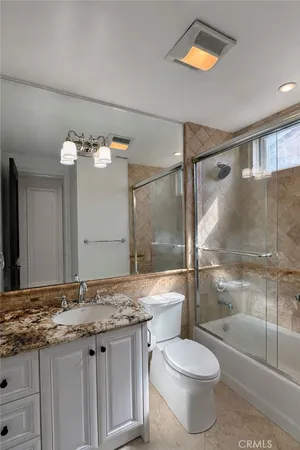 a bathroom with a granite countertop sink toilet and shower