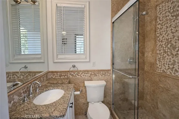 a bathroom with a granite countertop toilet sink and mirror
