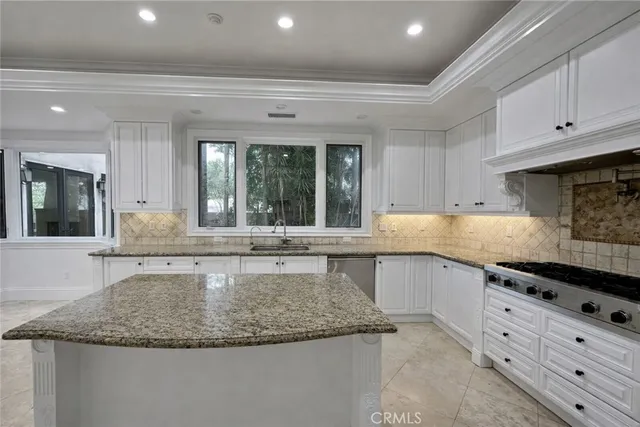 a large kitchen with granite countertop a sink and white cabinets