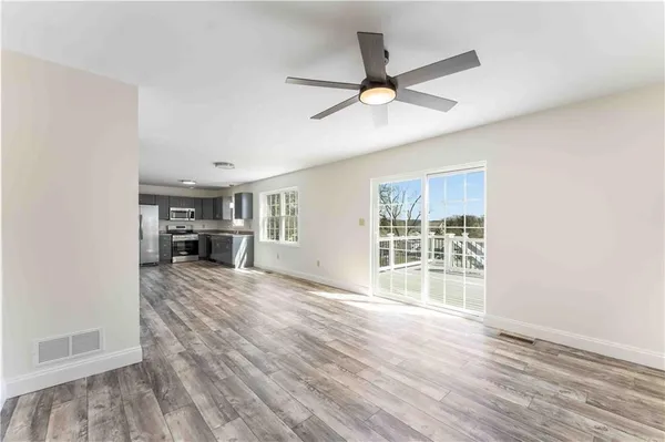 a view of empty room with wooden floor and fan