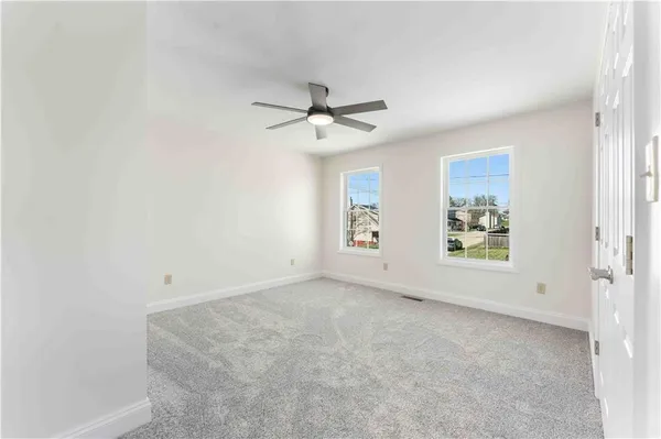 an empty room with windows and fan