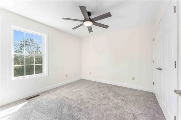 an empty room with ceiling fan and window