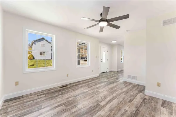 a view of an empty room with window and wooden floor