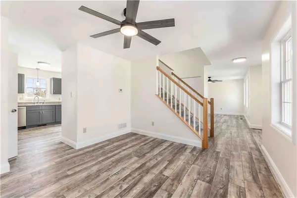 a view of a hallway with wooden floor and a kitchen