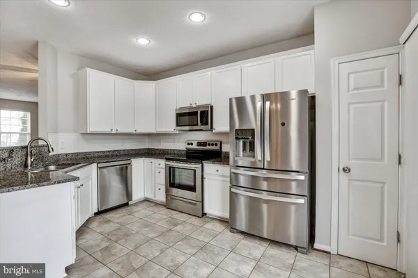 a kitchen with granite countertop a refrigerator stove and microwave